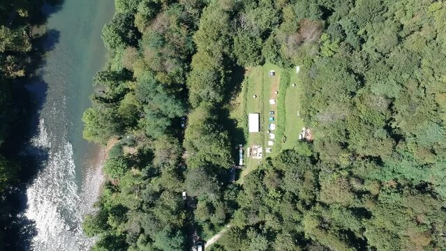 Boat sailing along the riverbank in green valley and a road among a dense forest. Kolpa, Slovenia