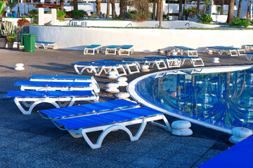 Terrace with sun loungers by the pool. Comfortable loungers beside the tranquil pool