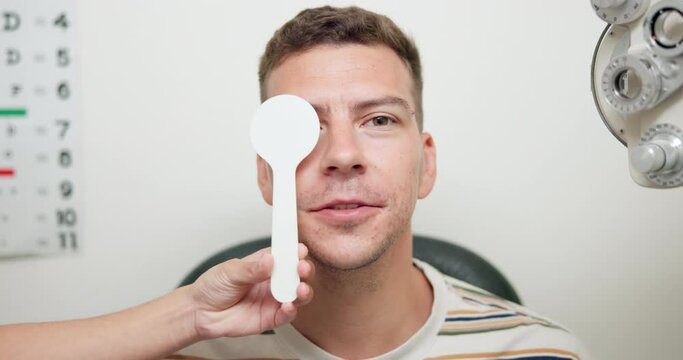 Man, reading and eye test with optometrist in office, vision or eyesight for glasses with optician holding occluder. Healthcare, sight examination in cover uncover, assessment for ocular deviation
