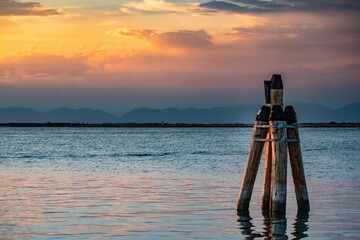 Scenic shot of wooden poles in the lagoon in Venice, Italy at sunset