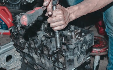Fototapeta premium Auto mechanic repairing the engine of a car with different tools