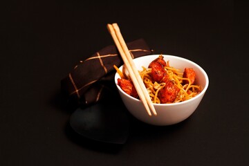 Closeup view of a bowl of noodles with Manchurian and Schezwan sauce isolated on black background