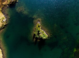 Aerial view of a small green land surrounded by Giglachseen lake in Austria