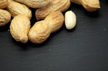 Closeup of a pile of peanuts isolated on a black background with copy space