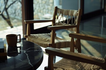 Close up photo of two wooden chairs with woven rope seats at a black marble table, with coffee and a book on the table, a window in the background, a modern architecture interior design