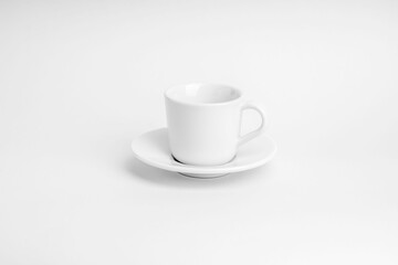 White cup of coffee with its plate on a white surface