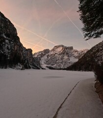 Winter landscape view with frozen Pragser Wildsee lake at sunrise, clear and purple sky background