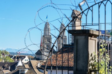 View of Grossmunster church through barbed wire on a metal gate. Zurich, Switzerland.