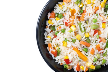 White rice with vegetables in a black bowl isolated on white background. Top view. Copy space - 781977541