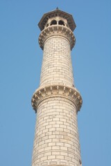 Vertical shot of the Taj Mahal tower against the blue sky