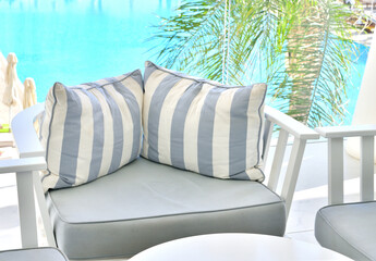 lounge with striped sofas against the backdrop of a pool of water