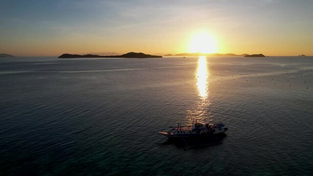 Traditional philippine boat bangka at sunset time in Linapacan, Philippines. Orange sky sunset paradise beach.