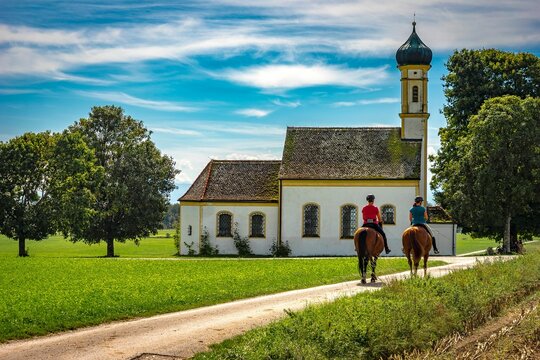 Horsemen riding towards St. Johann Chapel in Raisting, Germany