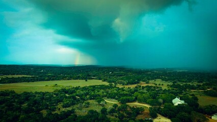 Fototapeta premium Aerial shot of trees on a field under a cloudy stormy sky