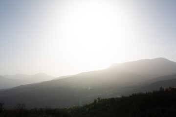 Mountains in a hazy haze against a background of blue sky and bright sunlight