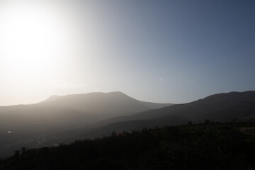 Mountains in a hazy haze against a background of blue sky and bright sunlight