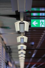 Vertical shot of the lights on the ceiling with an exit sign in the Reykjavik International Airport.