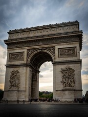 Fototapeta na wymiar Exterior of Arc de Triomphe under dramatic cloudy sky in Paris, France