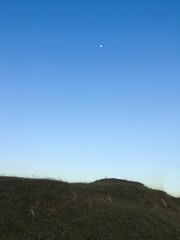 Vertical shot of the blue sky with a hill peeking below