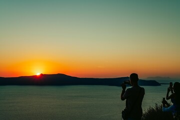 People taking photos of the sunset in Thira, Santorini, Greece