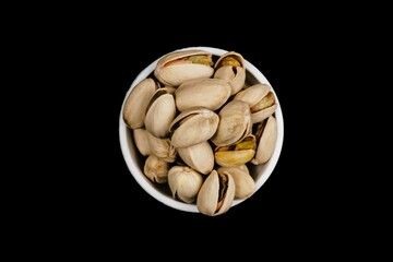 Lots Of Pistachios And Pistachio Shell In White Bowl, Isolated On Black Background