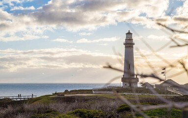a view from the beach looking at a lighthouse, the sky and water