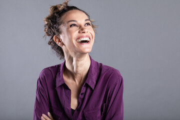 Close-up of a happy young girl wearing a lilac shirt smiling cheerfully. Emotional female
