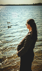 Pregnant girl with glasses on the background of the sea
