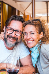 Portrait of happy adult couple posing for a picture sitting at the table restaurant in outdoor. Tourist having lunch on summer holiday vacation outdoor leisure activity together. Cheerful people smile