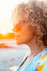 Side portrait of curly cute woman with sunset sunlight in background in outdoor leisure activity alone. Attractive long hair female people adult in contemplation. People lifestyle. Cute lady.