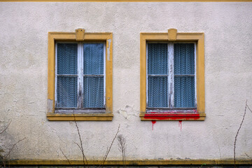 Two windows next to each other of an abandoned house with red coloured window sill - 782002129