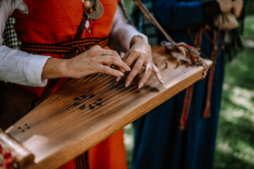 Valmiera, Latvia - July 14, 2023 - Hands playing a kokle, a traditional Latvian stringed musical...
