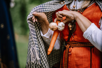 Valmiera, Latvia - July 14, 2023 - Hands holding garlic and a carrot in front of a person wearing a...