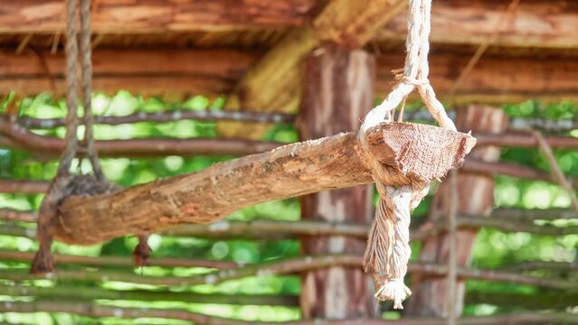 Old wooden shelf hangs on ropes under canopy. It is intended for drying dried products.