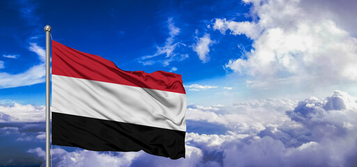 Yemen national flag cloth fabric waving on beautiful Blue Sky Background.