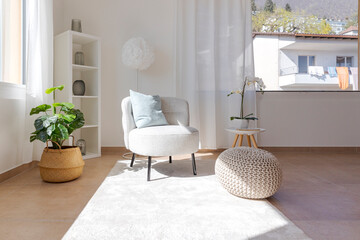 Detail of a living room corner with a small armchair with a coffee table and a pouf resting on the carpet - 782011300