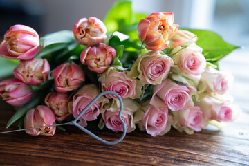 Beautiful bouquet of pink roses and tulips with a heart shape on dark wood for mother's day greetings.