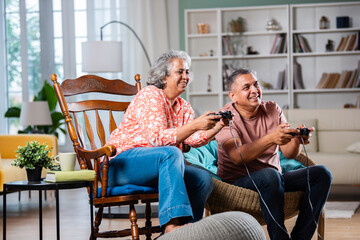 Happy Indian asian mid age couple having fun, playing video game together