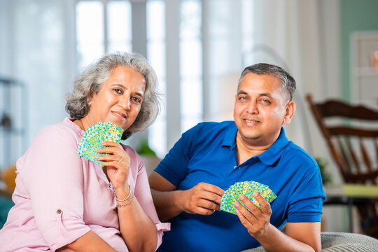 Mature Indian couple enjoying while playing cards together at home.