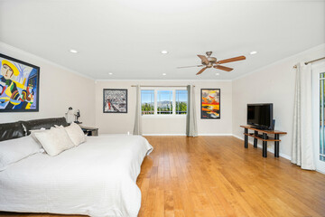 Minimalist bedroom with wooden floors, white walls in Encino, California