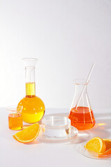 Transparent podium in round shaped for displaying product arranged with a boiling flask, erlenmeyer flask, beaker of orange liquid. showcase for product made from natural orange extract