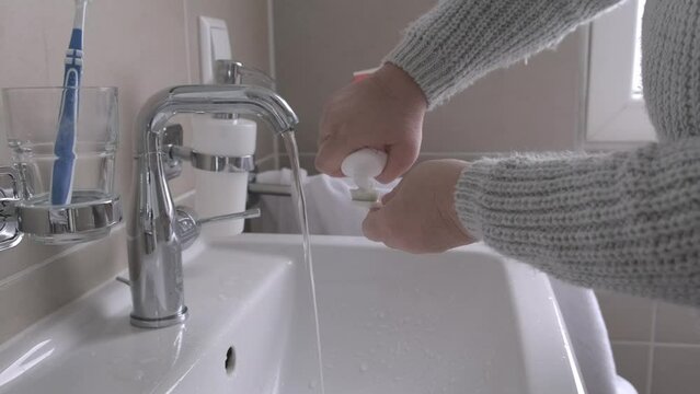 mature woman diligently brushes teeth and rinses her mouth with water over bathroom sink after eating, dental cleanliness, Maintaining good oral health through regular brushing