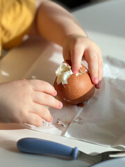 Baby hands shelling boiled egg. Breakfast time. Closeup view