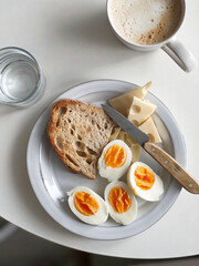 Hard boiled eggs, whole grain bread toast and cheese served with cup of coffee. Healthy breakfast meal. Top view