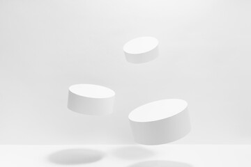 Set of three round tilt white podiums for cosmetic products mockup, soar in hard light, shadow on white background. Stage for presentation skin care products, gifts, goods, advertising, design, sale.