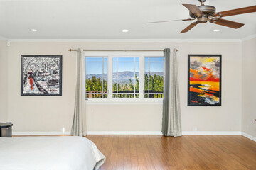 Cozy bedroom with hardwood floors, spacious bed, and two wall paintings in Encino, CA