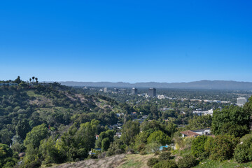 Fototapeta na wymiar Lush green hill, trees, rolling hills, and clouds in Hidden Hills, CA