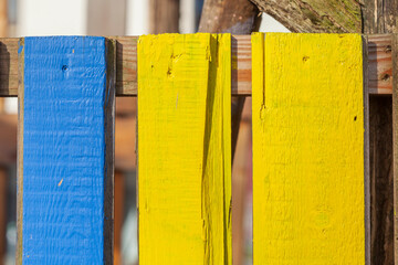 Blauer und gelber Bretterzaun aus Holz, Deutschland - obrazy, fototapety, plakaty