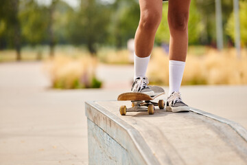 A young African American woman skateboarding on a ledge at an outdoor skate park. - obrazy, fototapety, plakaty