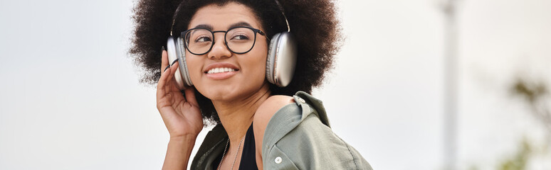 A young woman in a jacket listens to music through headphones while embodying the rhythm in an...